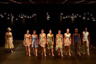 group of dancers in a line under hanging lights